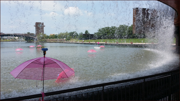 環水公園。人工の滝の向こうに傘のオブジェ