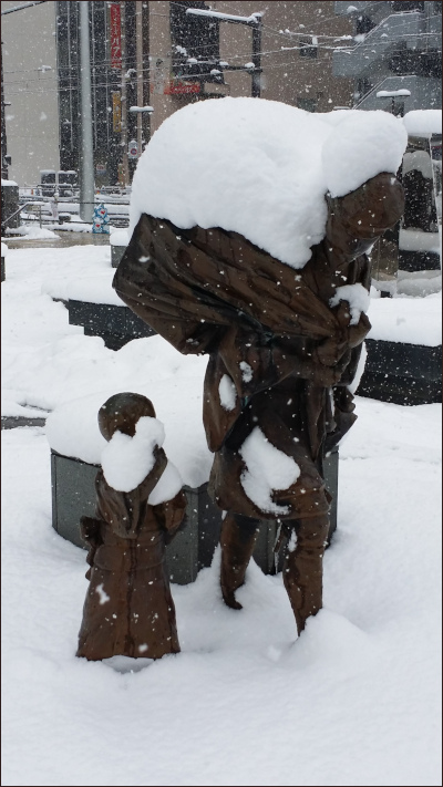 雪の積もった売薬さんの銅像